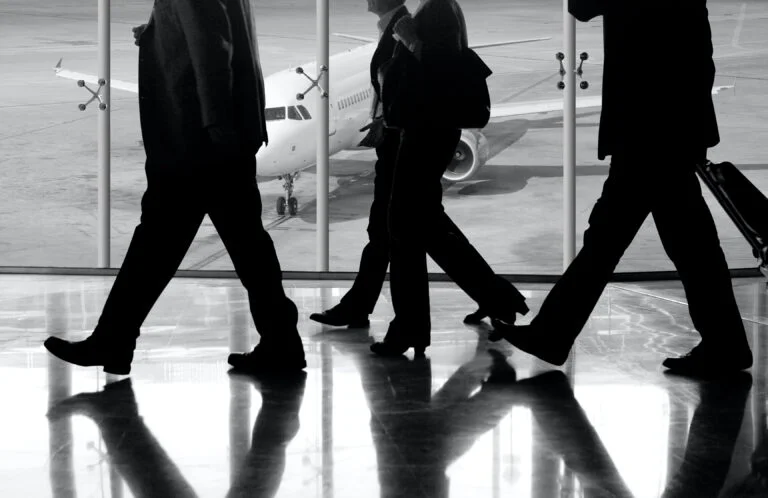 Three businessmen preparing for business travel to South Korea walking down the airport.