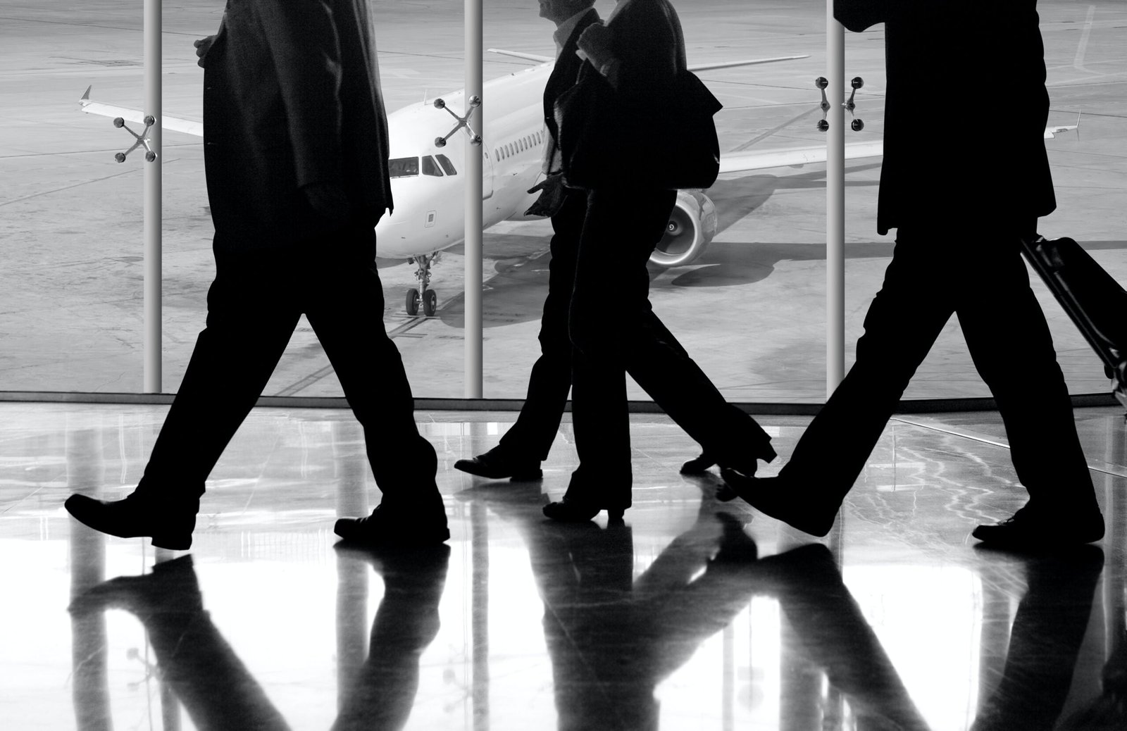 Three businessmen preparing for business travel to South Korea walking down the airport.