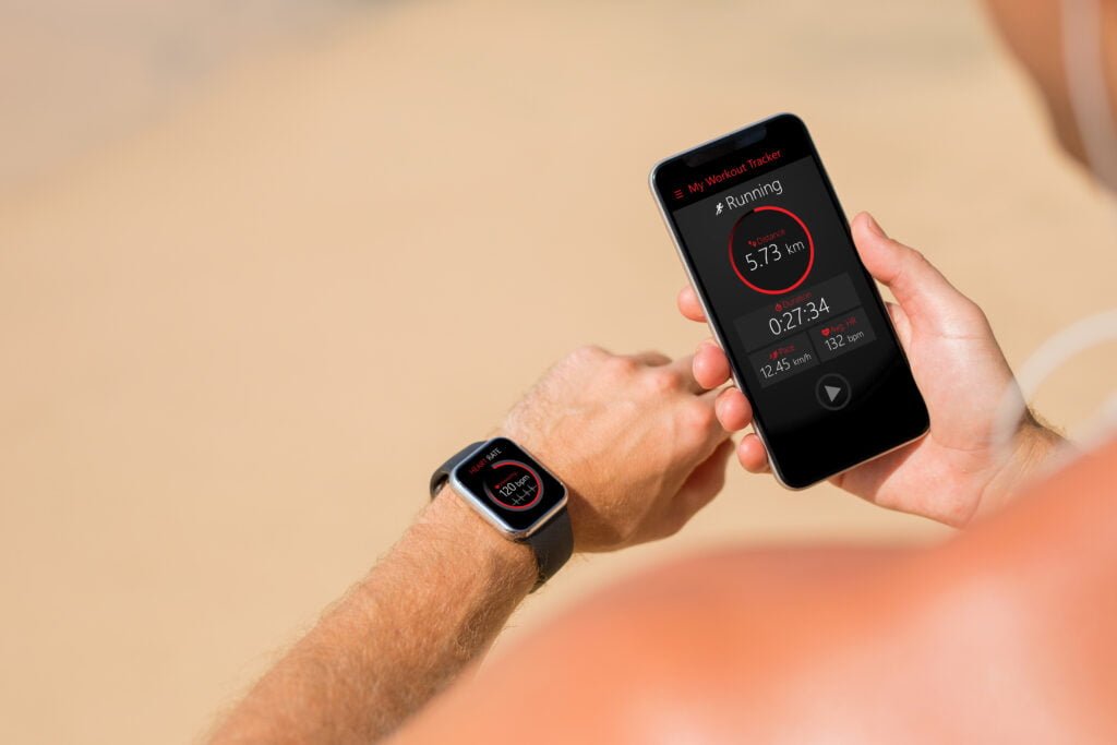 Person with wearable health tech watch combined with their phone monitoring their health.